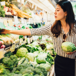woman holding cabbage while shopping for veggies at the supermarket